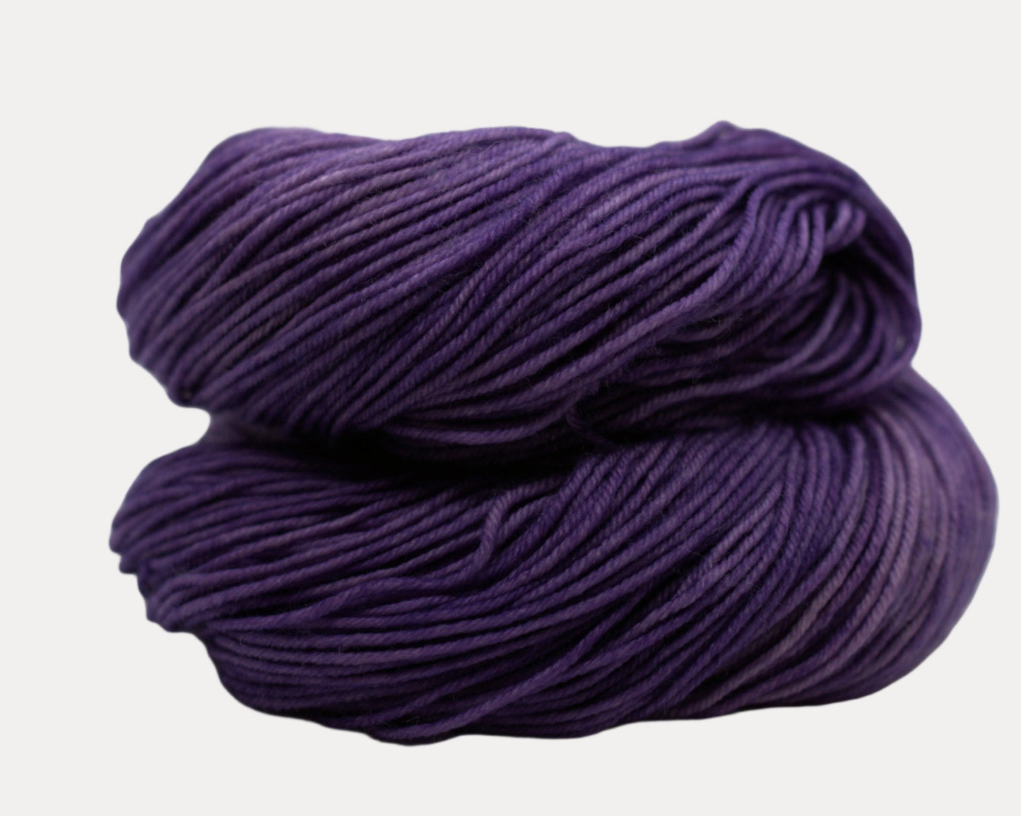 curled up skein lavender colored yarn on white background.