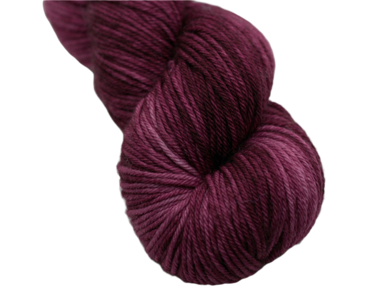 close up twisted skein tonal red plum colored yarn on white background.