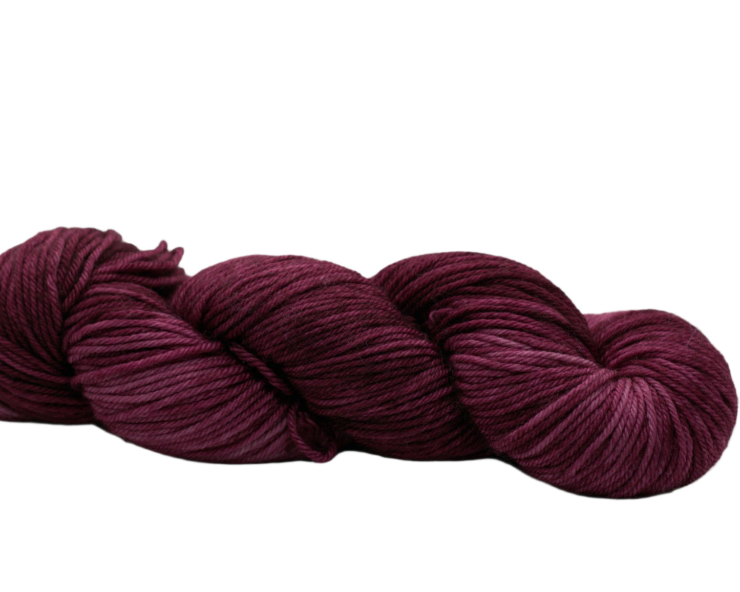 side view of twisted skein tonal red plum colored yarn on white background.