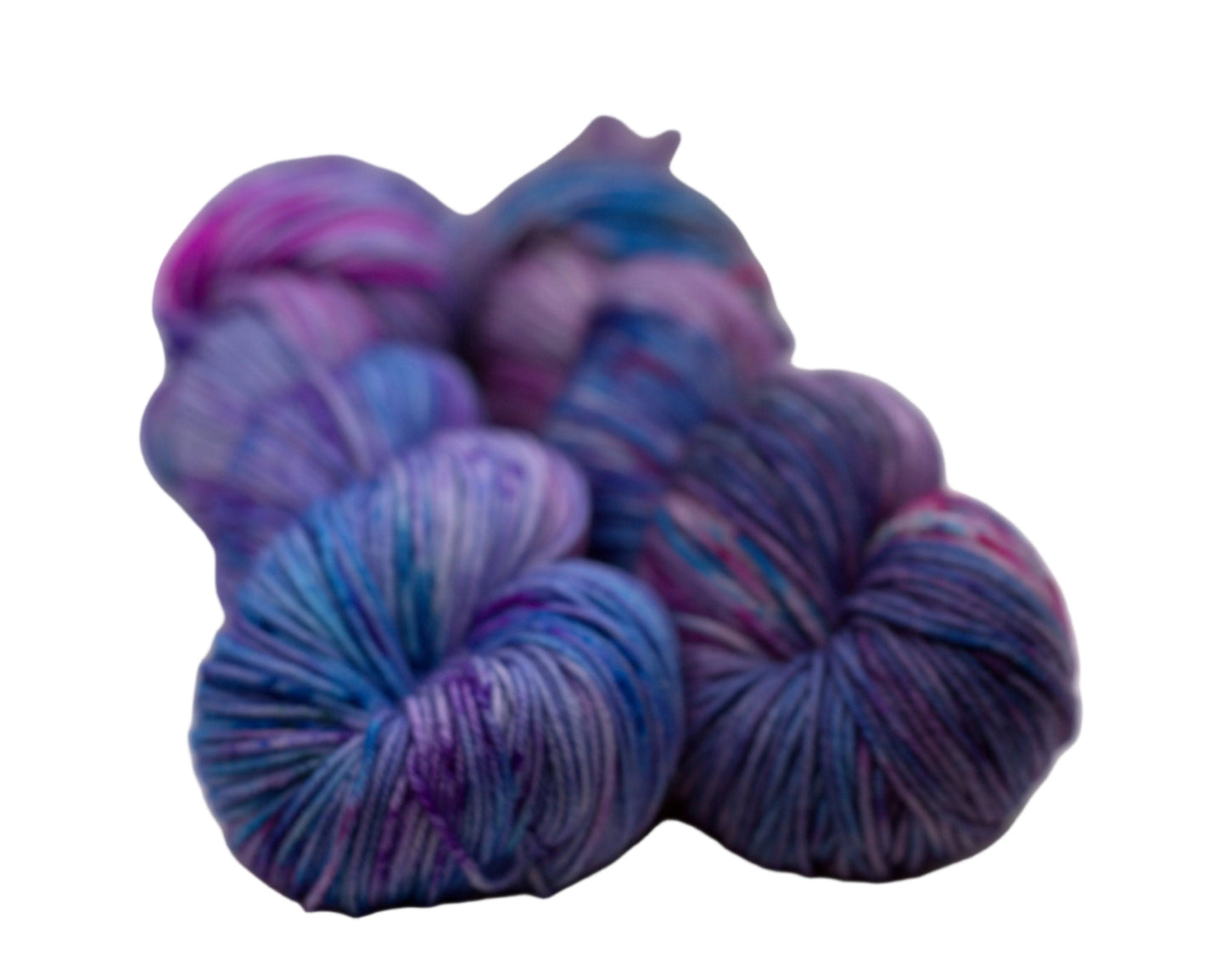 two twisted skeins of light purple yarn with turquoise, magenta and black speckles on white background.