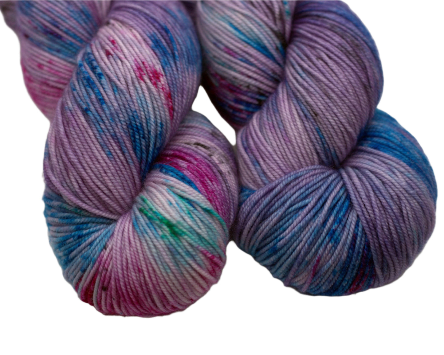 close up of two twisted skeins of light purple yarn with turquoise, magenta and black speckles on white background.