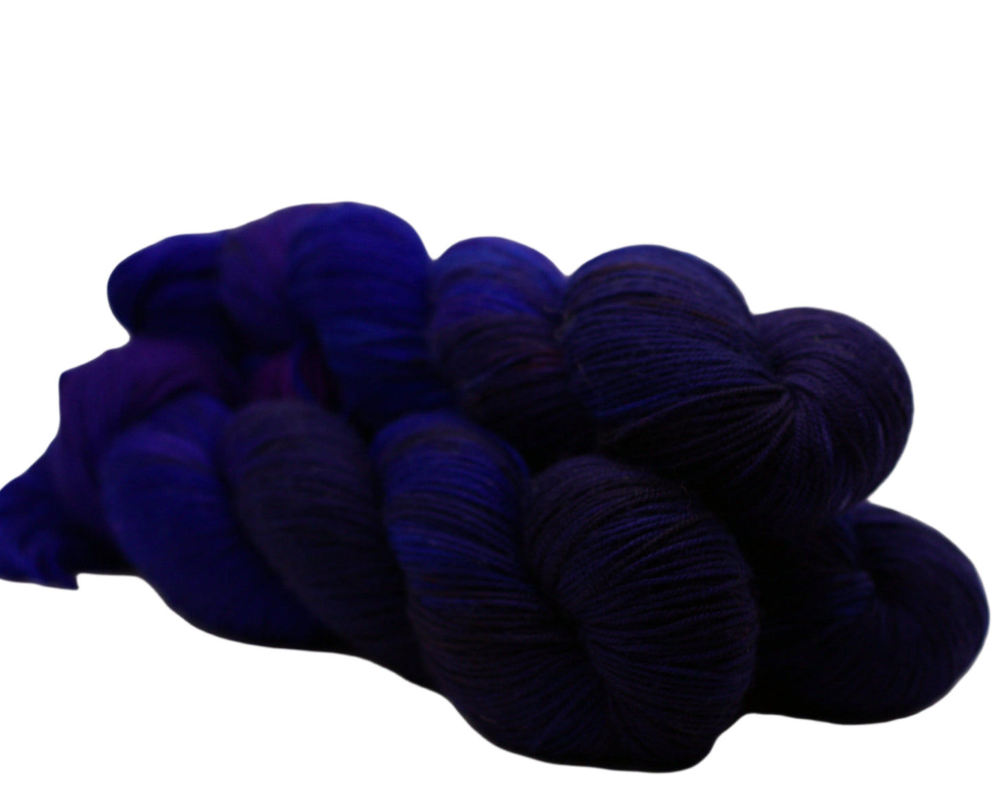Side view of three skeins of blue layered over red yarn on white background.