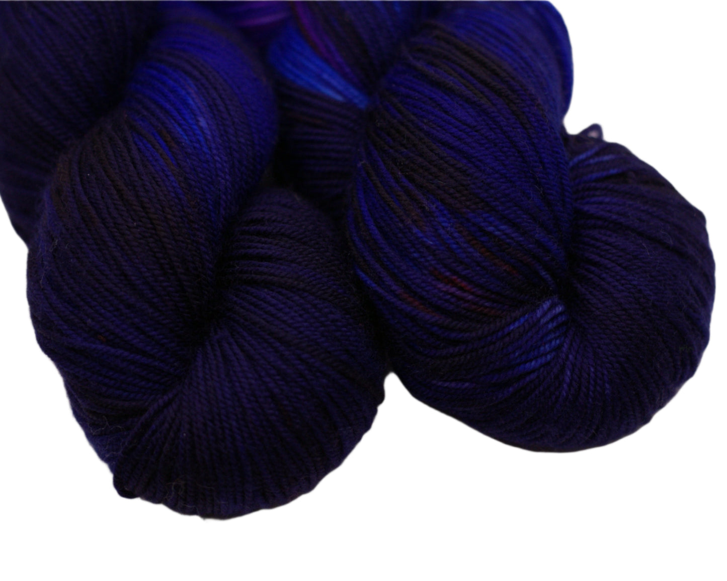 Close up of two twisted skeins of blue layered over red yarn on white background.