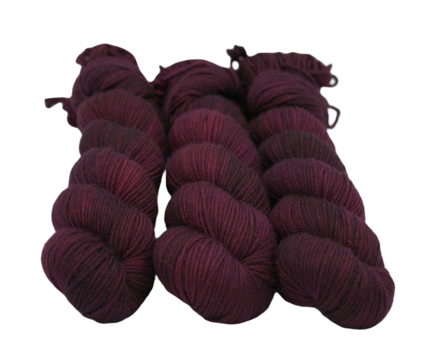 three twisted skeins variegated tonal burgundy yarn on white background.