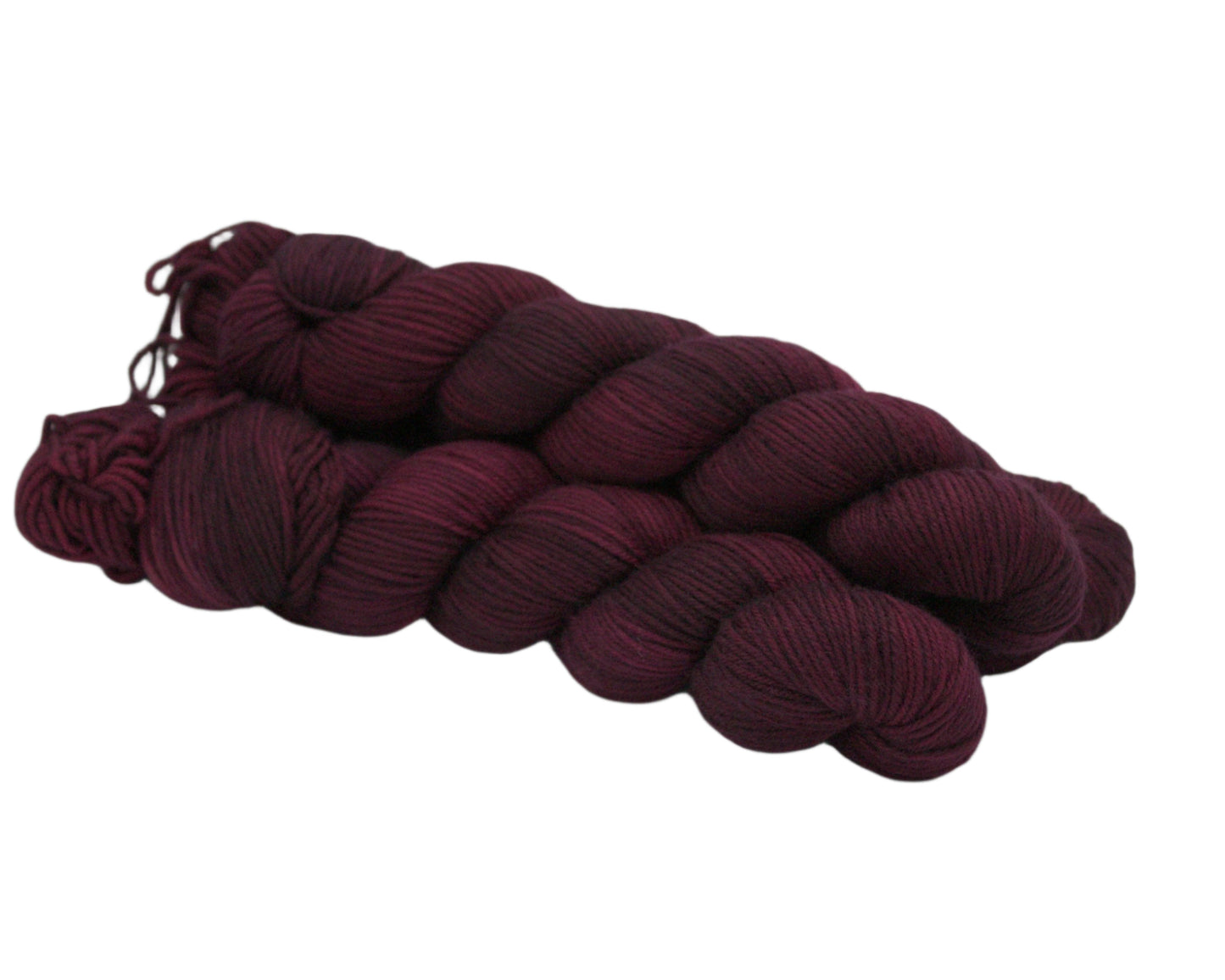 side view of three twisted skeins tonal burgundy colored yarn on white background.