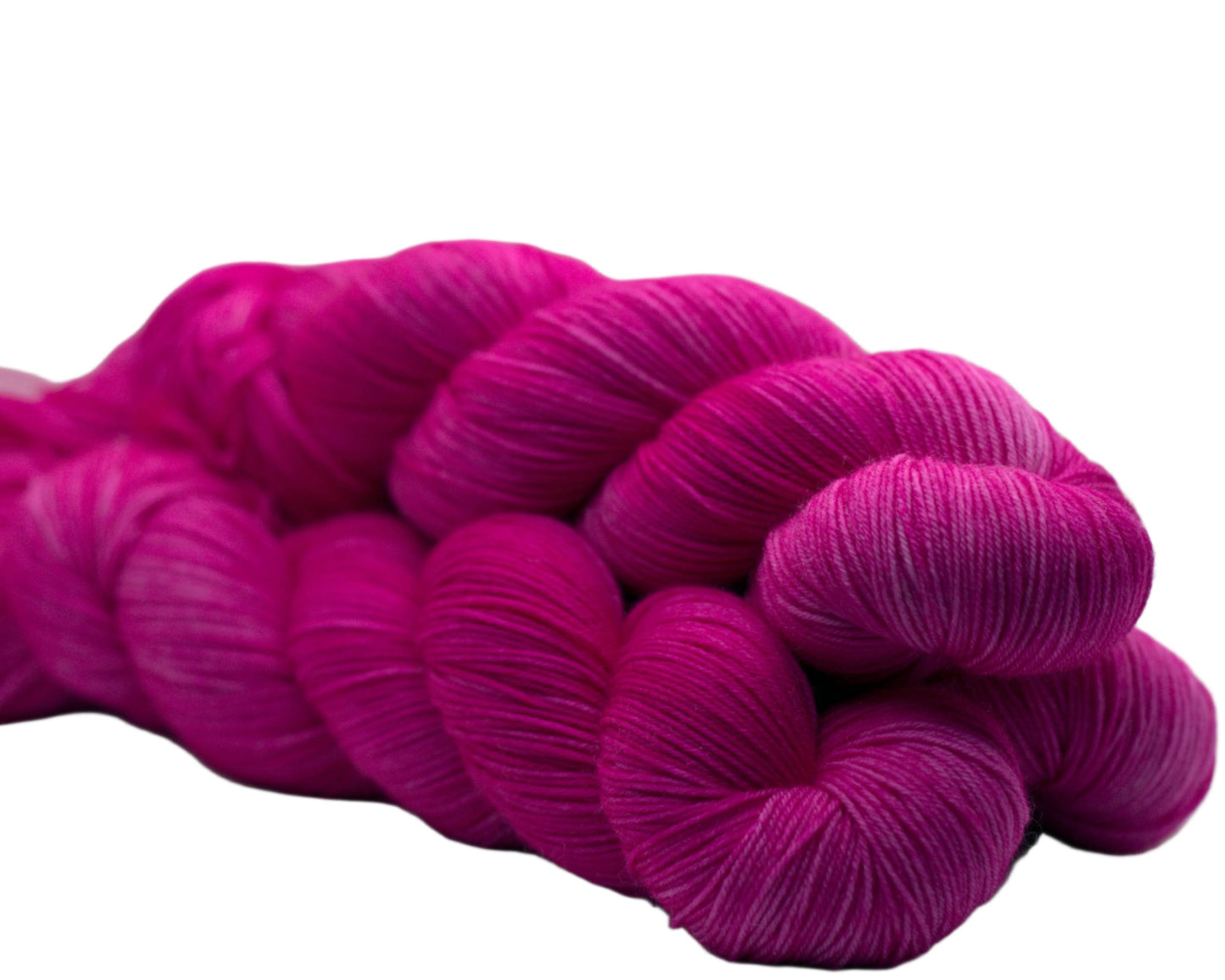 side view of three twisted skeins tonal bright pink yarn on white background.