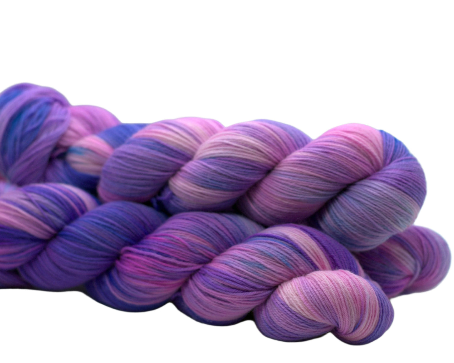 Side view of three twisted skeins of variegated pink, purple and blue yarn on a white background.