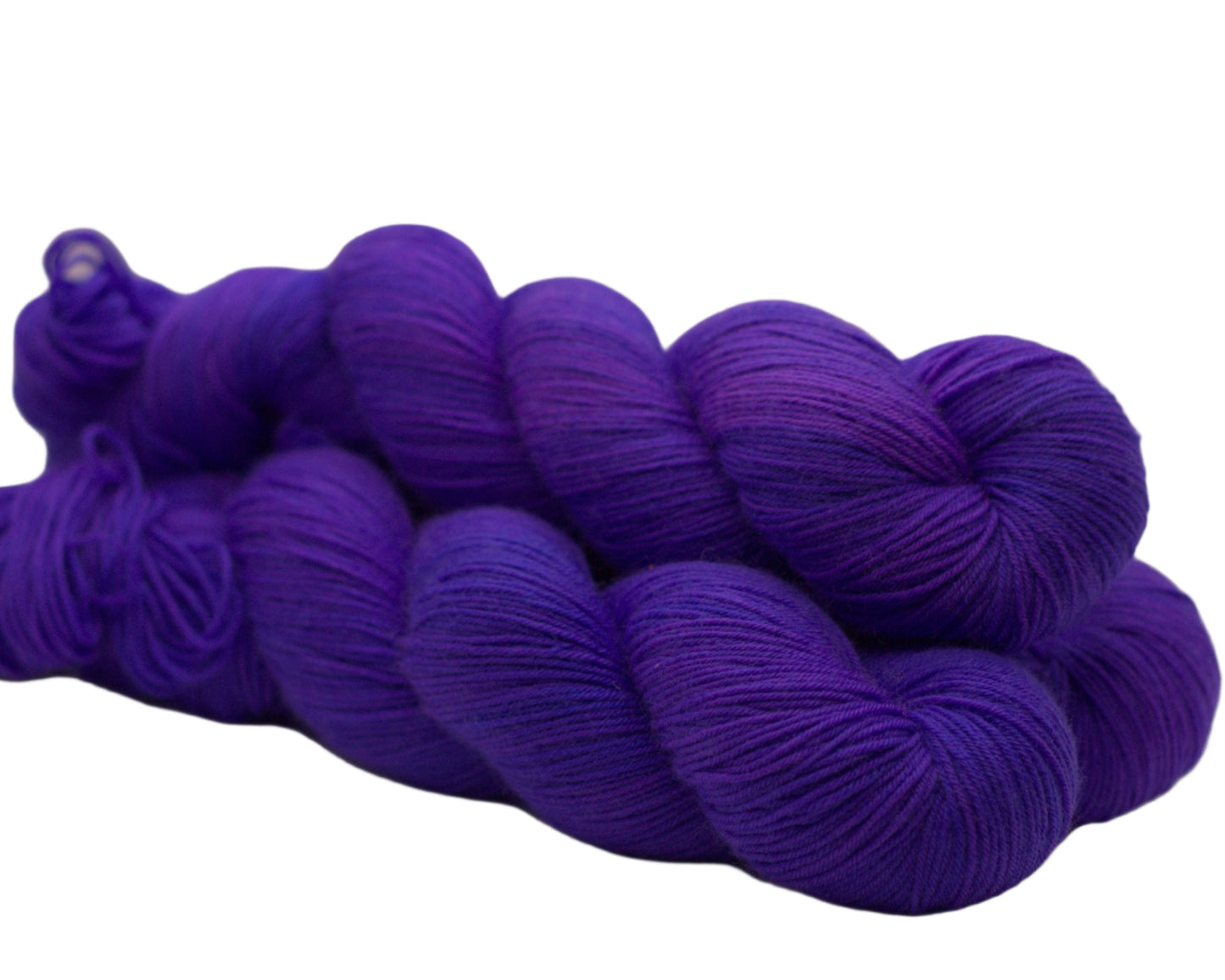 Side view of three twisted skeins of purply-blue yarn on a white background.