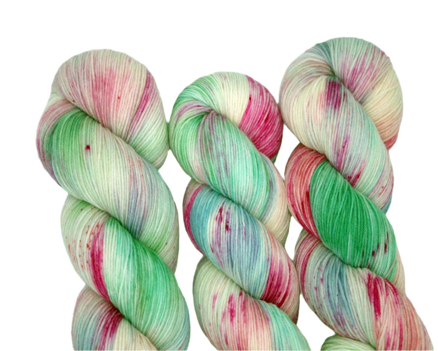 close up of three twisted skeins pink, blue and green speckled yarn on white background.