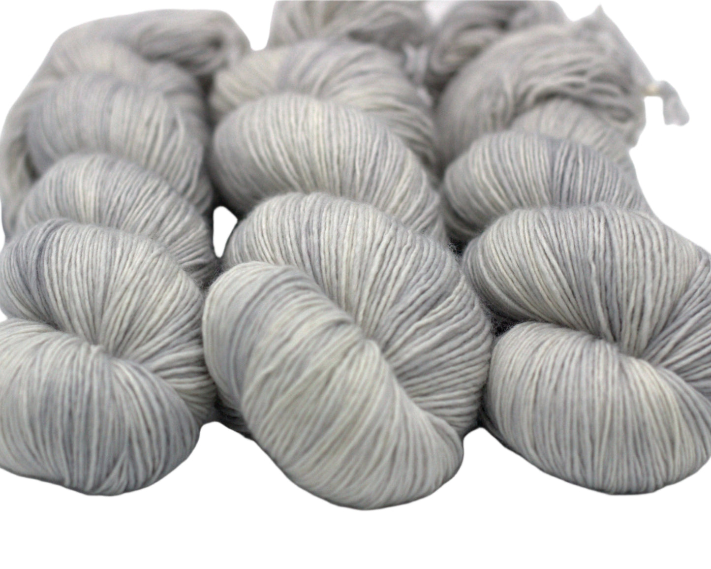 three twisted skeins tonal silver yarn on white background.