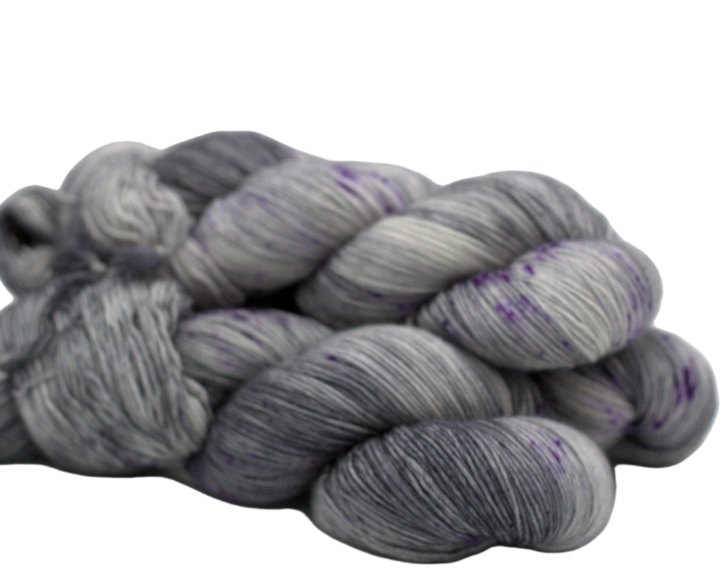 side view of three twisted skeins tonal dark silver yarn with purple speckles on white background.