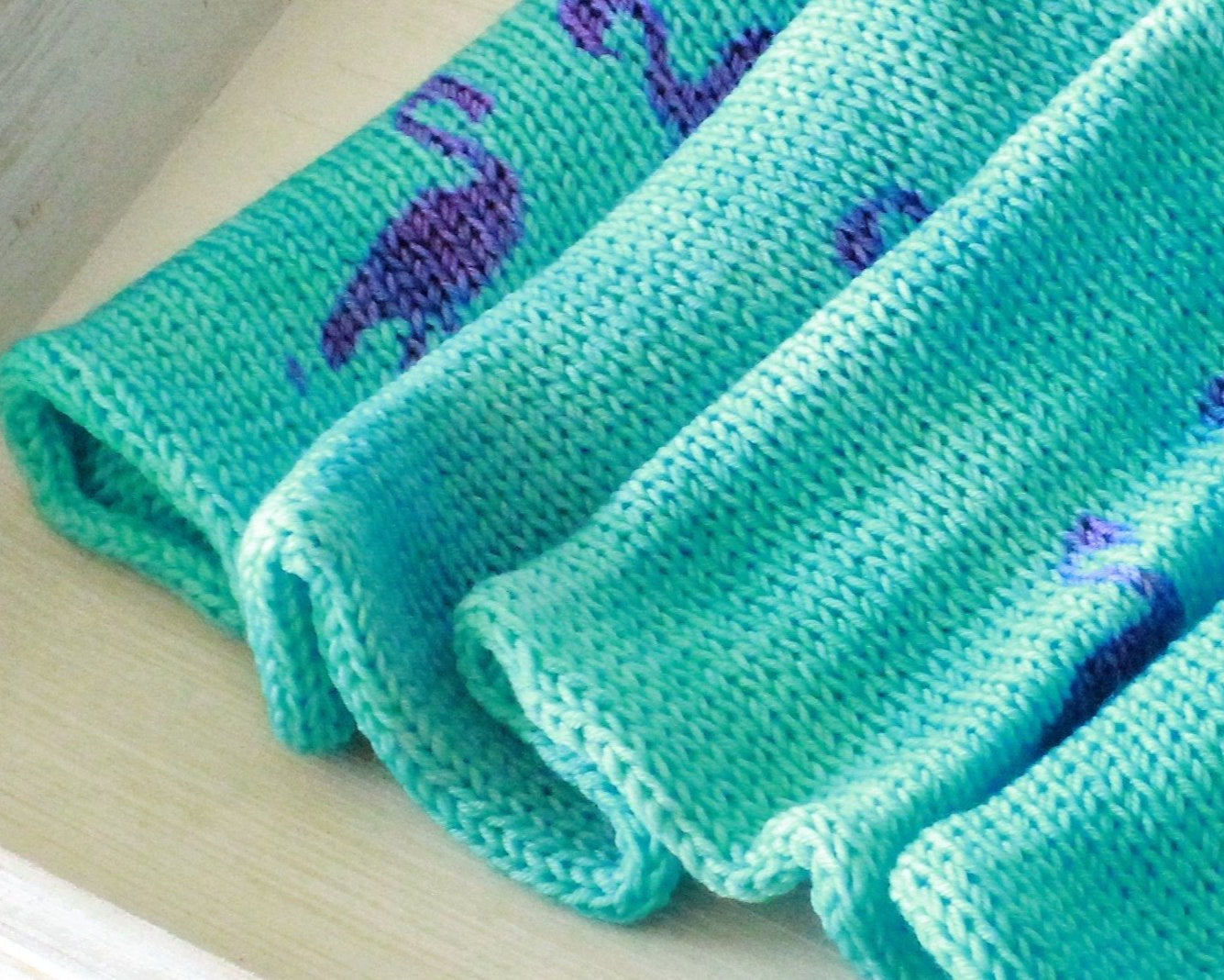 close up top view of sock blank that is turquoise in color with magenta flamingo stencils