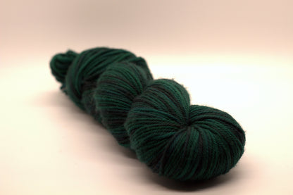 twisted skein variegated dark green and black yarn on white background.