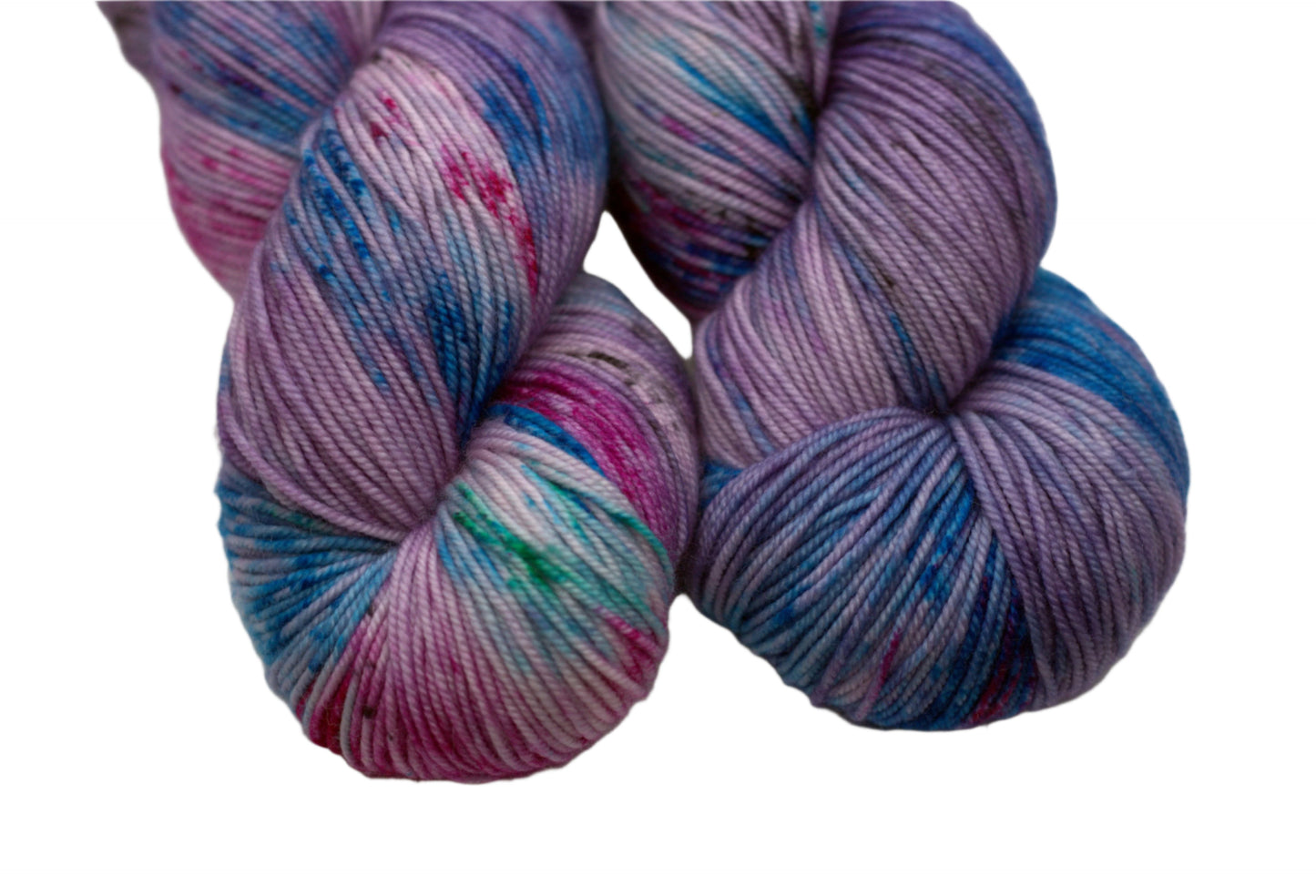 close up of two twisted skeins of  light purple yarn with turquoise, magenta and black speckles on white background.