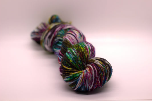twisted skein of multicolored speckled yarn on white background.