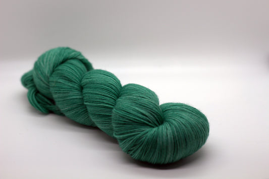 One twisted skein of green yarn on a white background