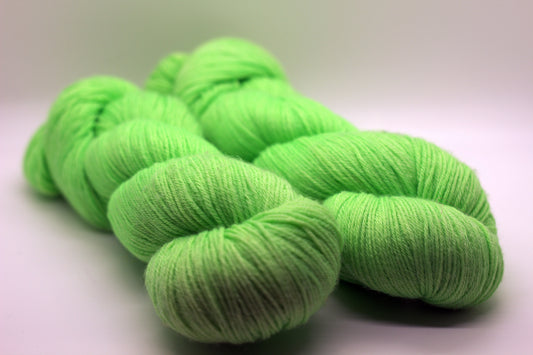 Two twisted skeins of light green yarn on a white background