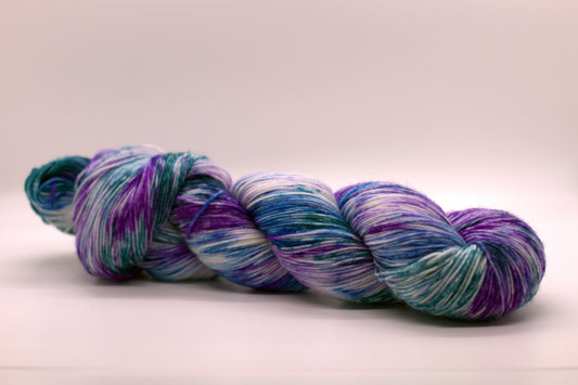One twisted skein blue, purple and teal variegated yarn on white background.l