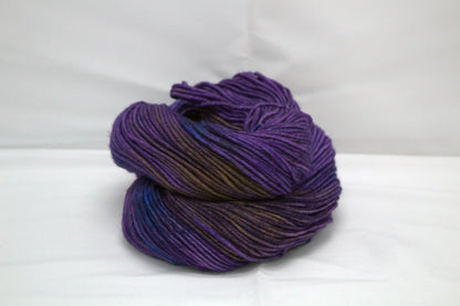 curled up skein of variegated purple yarn on white background.