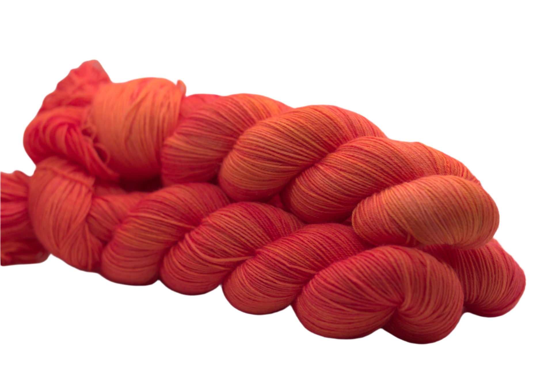 side view of three twisted skeins orange yarn with yellow undertones on white background.