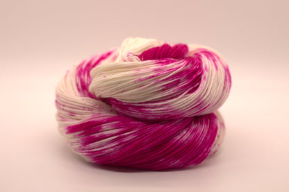 one curled up skein bright pink speckled yarn on white background.