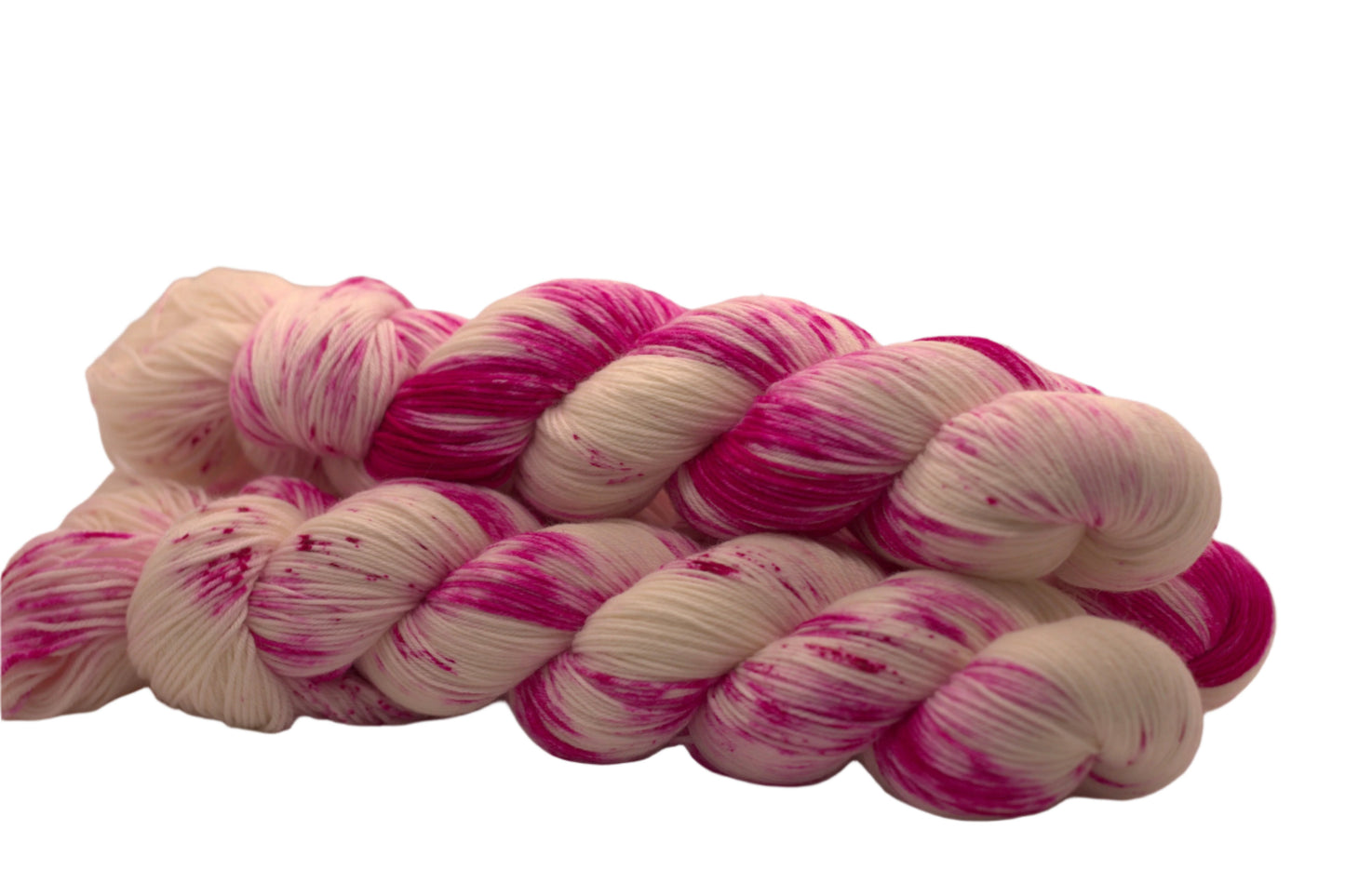 side view of three twisted skeins bright pink speckled yarn on white background.